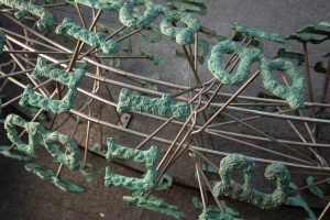A zoom into the fine details of the patinated finish of the letters that make up Broken English