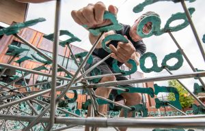 Artist Greg Gomez making the final adjustments during his instillation
